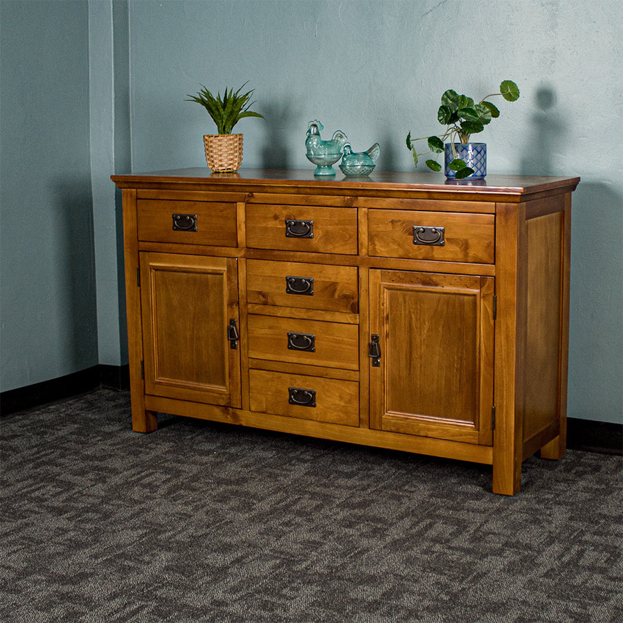 Front view of the Montreal Rimu Stained Buffet/Sideboard, there are two blue glass ornaments and two potted plants on top.