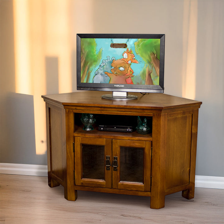The front of the Montreal Pine Corner Entertainment Unit with a TV on top. There is a DVD player and two blue glass ornaments on the shelf.