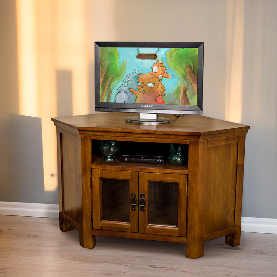 The front of the Montreal Pine Corner Entertainment Unit with a TV on top. There is a DVD player and two blue glass ornaments on the shelf.