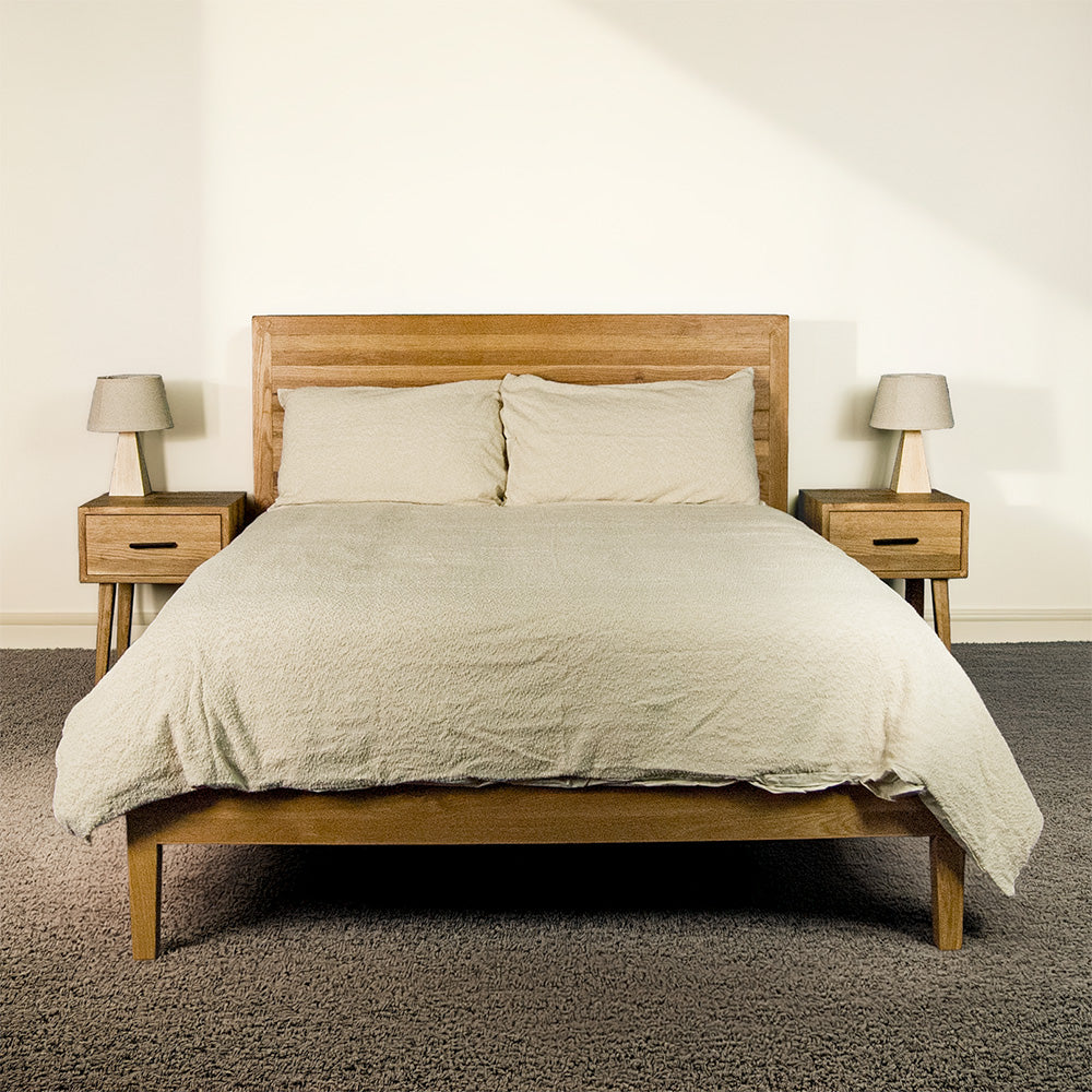 The front of the Ormond Oak Double Bed Frame with sheets and pillows on top.