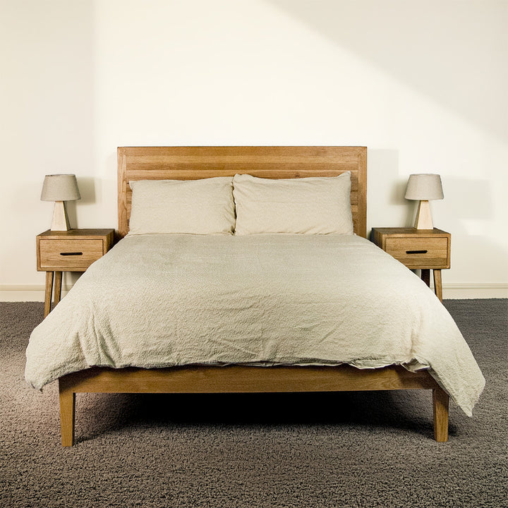 The front of the Ormond Oak Double Bed Frame with sheets and pillows on top.