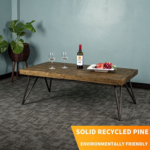 Front view of the Paddington Recycled Pine Coffee Table. There is a fruit platter, two glasses and a glass bottle on top. There is a standing potted plant in the background.