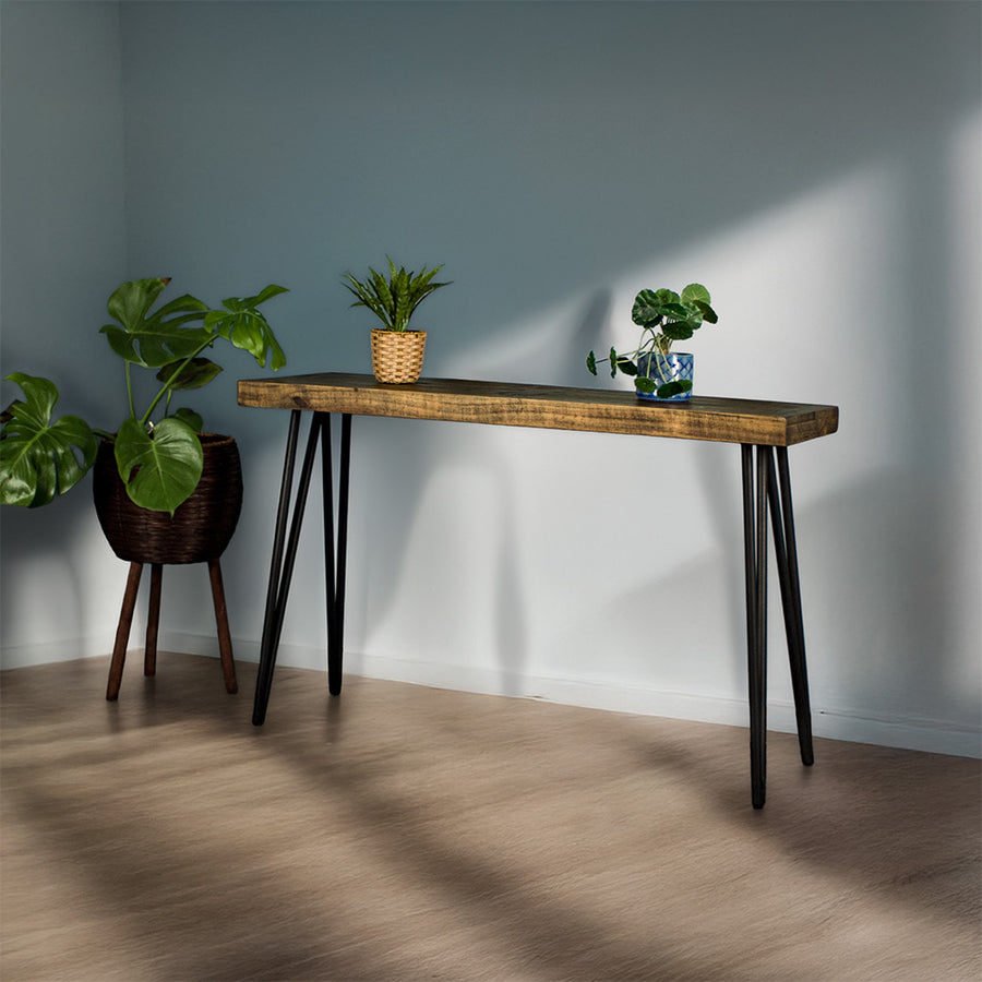 The front of the Paddington Hall Table. There are two potted plants on top with a free standing potted plant next to it.