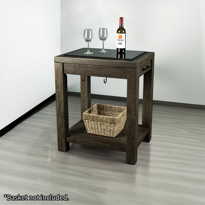Front view of the Stonemill Recycled Pine Granite Workbench. There are two glasses and a bottle on the granite top, and a woven basket on the lower shelf.