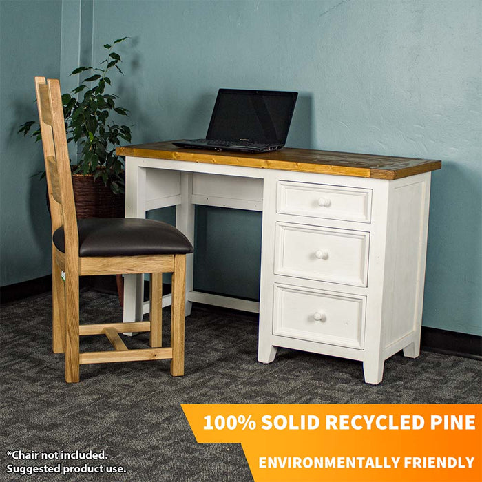 The front of the Tuscan Recycled Pine Small Desk. There is a laptop on top and an oak upholstered dining chair in front. There is a free standing potted plant next to it.