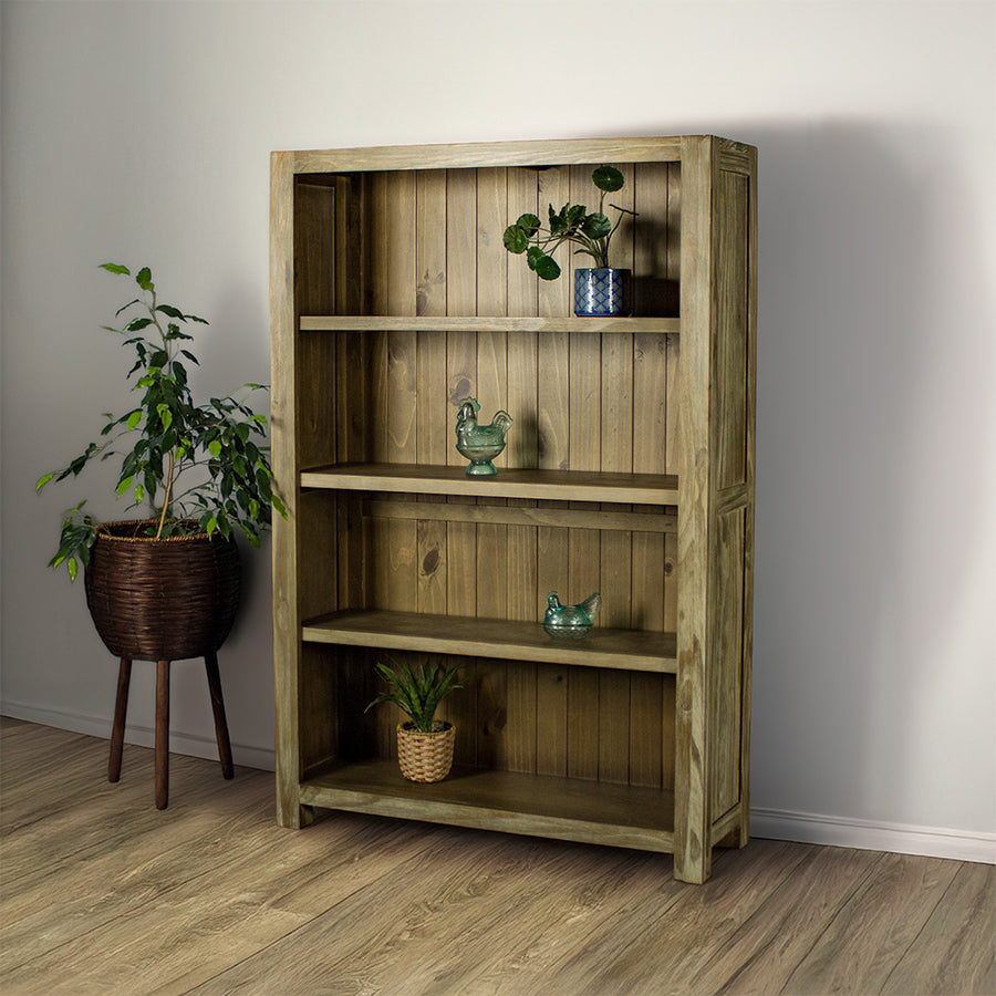 The front of the Vancouver 1.5 m Pine Bookcase. There is a potted plant on the top shelf, a blue glass ornament on the second shelf, a blue glass ornament on the third shelf and a potted plant on the lowest shelf. There is a free standing potted plant next to the bookshelf.