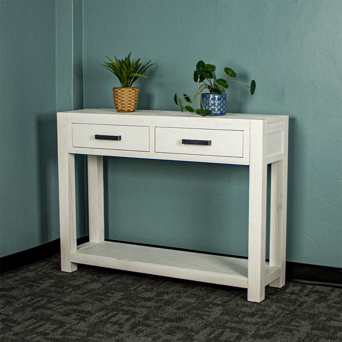 Vancouver 2 Drawer White Pine Hall Table front view. There are two potted plants on top.