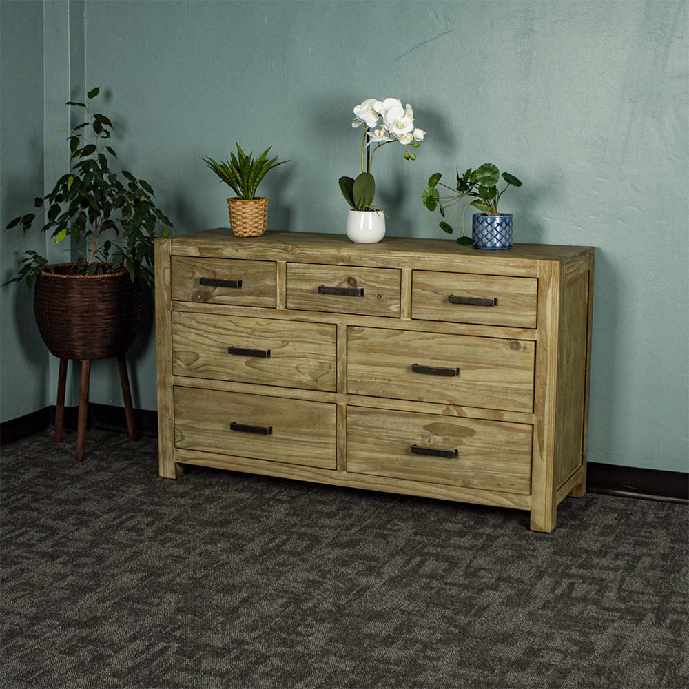 The front of the Vancouver 7 Drawer NZ Pine Lowboy. There are three potted plants on top, with a free standing potted plant next to the lowboy.