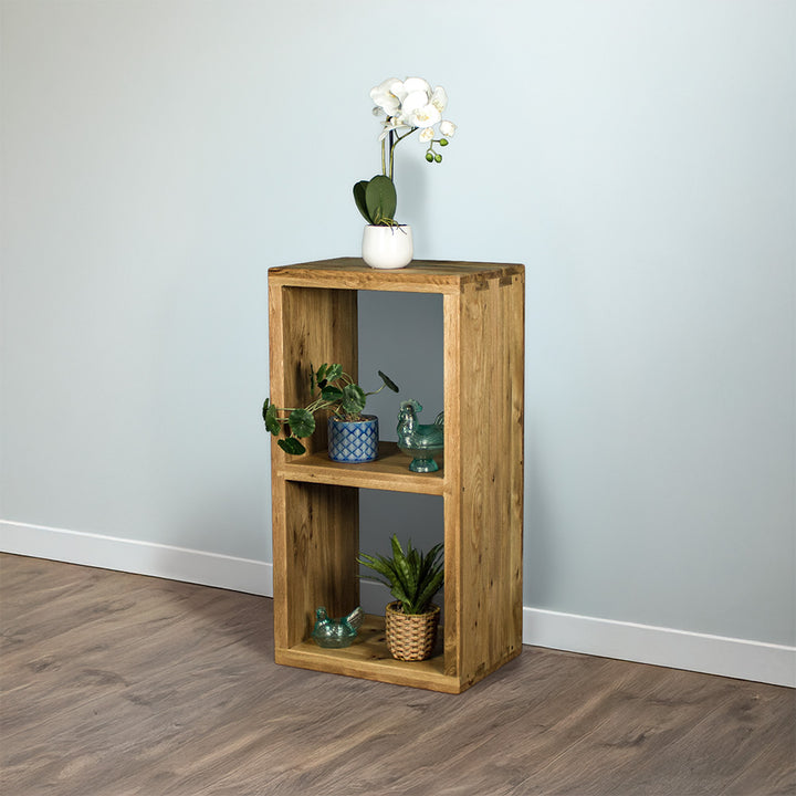 The front of the Vancouver Value Double Cube Oak Shelf with a white pot of white flowers on top, a potted plant and blue glass ornament on the top shelf and a blue glass ornament and potted plant on the bottom shelf.