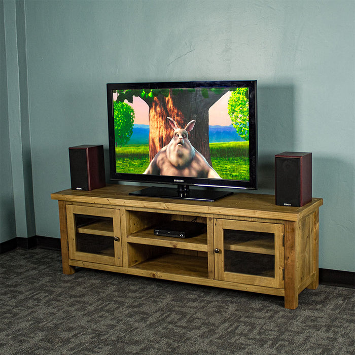 An overall view of the Ventura Recycled Pine Medium TV Unit. There is a TV on top, with two bookcase speakers on either side and a DVD player on the top shelf in the middle of the unit.