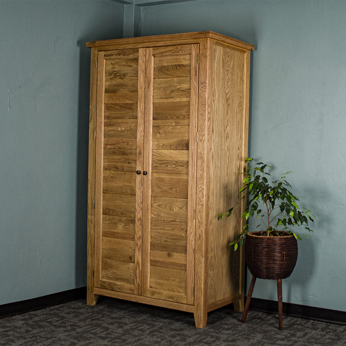 The front of the Vienna Oak Large Wardrobe. There is a free standing potted plant next to it.