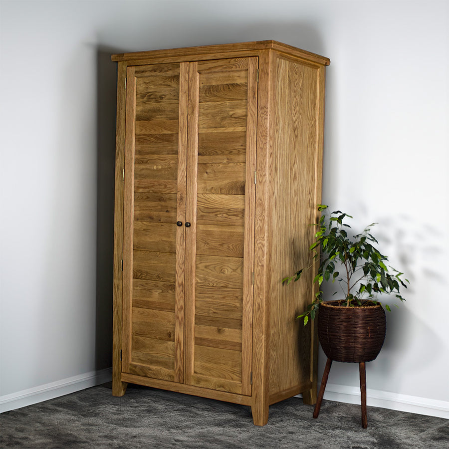 The front of the Vienna Oak Large Wardrobe. There is a free standing potted plant next to it.