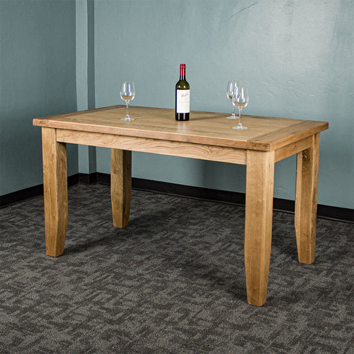 The front of the Yes Oak Dining Table (1.4m). There are three wine glasses on top and a glass bottle.