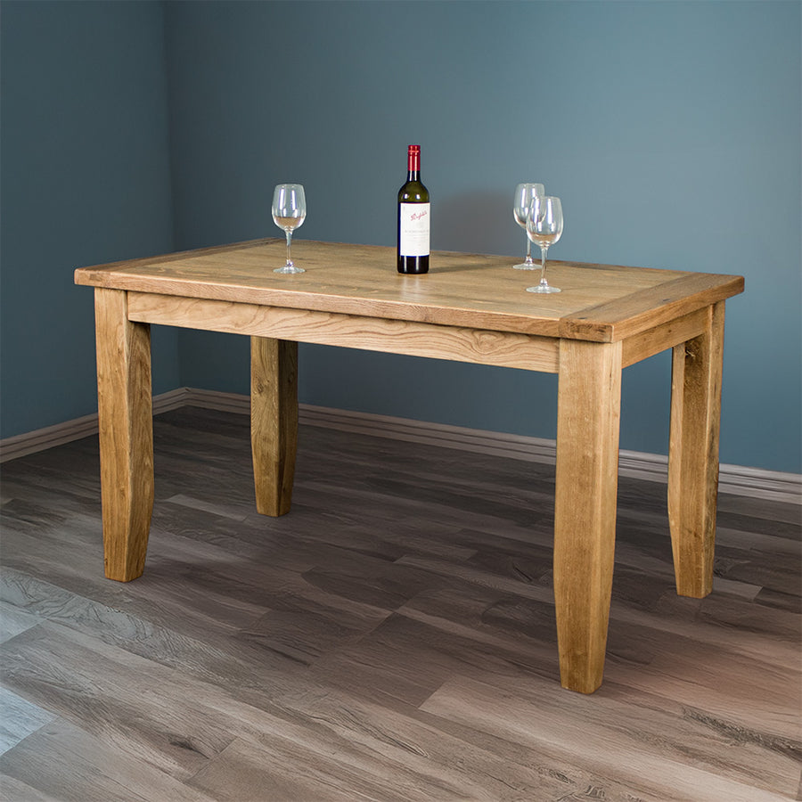 The front of the Yes Oak Dining Table (1.4m). There are three wine glasses on top and a glass bottle.