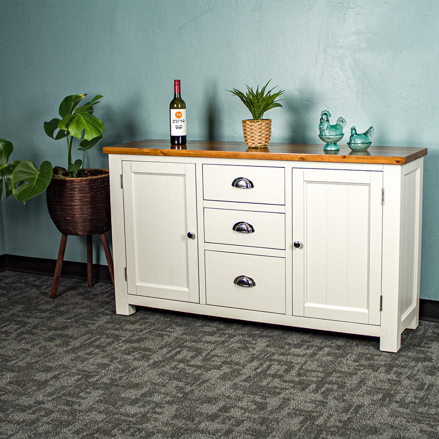 White Alton 2 Door 5 Drawer Buffet with Rimu stained top, there is a glass bottle, a potted plant and two small glass ornaments on the top.