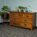 The front of the Montreal 7 Drawer Pine Lowboy. There are two blue glass ornaments on top with two potted plants in between. There is a free standing potted plant next to the lowboy.