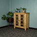 The front of the Yes Oak Display Cabinet. There are two blue glass ornaments on the middle shelves and two potted plants on top. There is a free standing potted plant next to the cabinet.