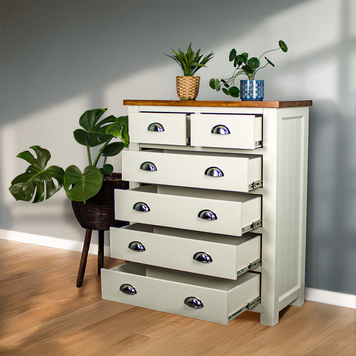 An overall view of the Alton 6 Drawer NZ Pine Tallboy with its drawers open. There is a free standing potted plant next to it. There are two potted plants on top