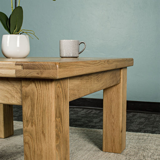 The side of the Amstel Square Oak Coffee Table. There is a coffee mug on top.