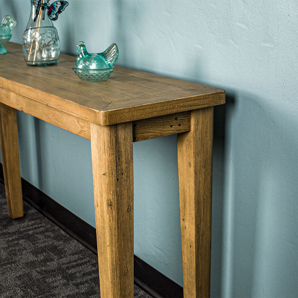 Side view of the Cairns Recycled Pine Hall Table. One of the blue glass ornaments can be seen as well as the lower half of the blue glass vase on top of the table.