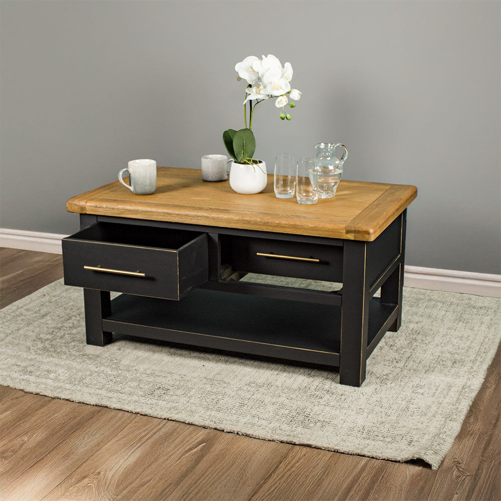 The front of the Cascais 2 Drawer Coffee Table with its drawers open. There is a pot of white flowers on top, two coffee mugs, a pitcher of water and two glasses on top.