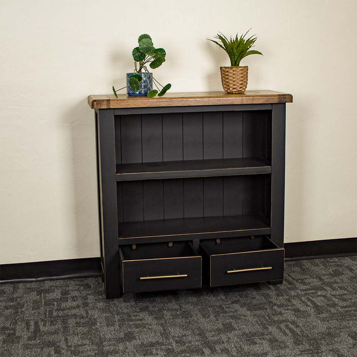 The front of the Cascais Oak Low Bookcase with its drawers open. There are two potted plants on top.