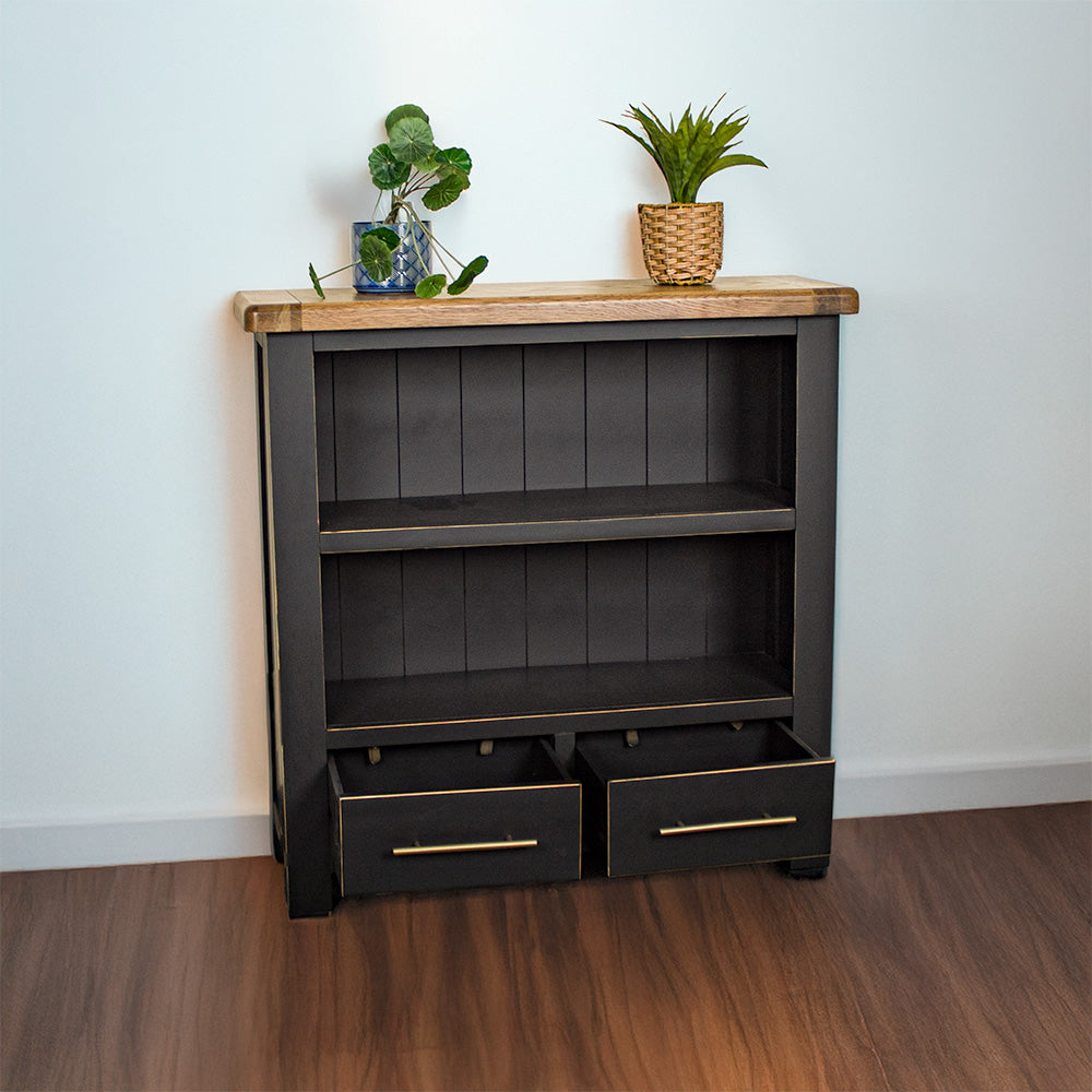 The front of the Cascais Oak Low Bookcase with its drawers open. There are two potted plants on top.