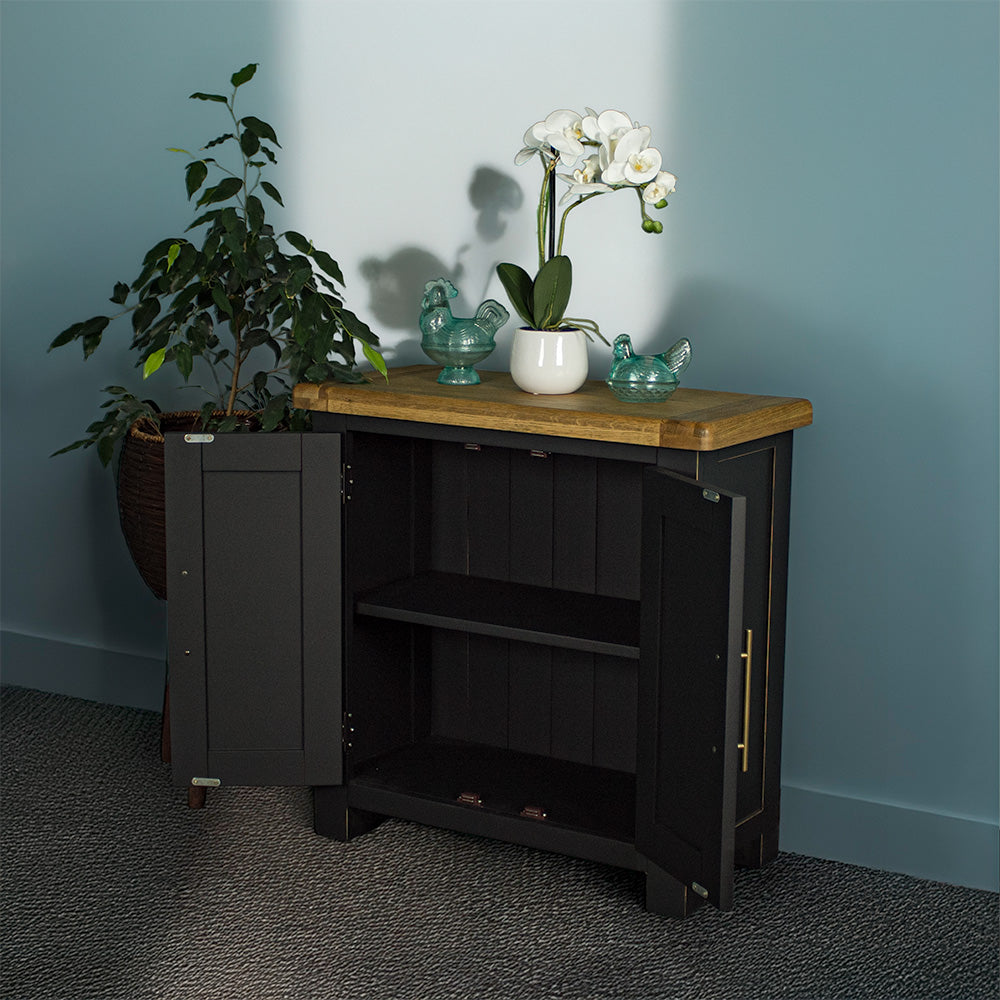 The front of the Cascais Oak-Top Small Sideboard with its doors open. There are two blue glass ornaments on top with a small pot of white flowers in between.