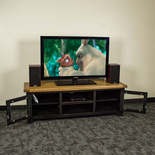 An overall view of the Cascais 2 Door Medium Entertainment Unit with its doors open. There is a large TV with two speakers on either side. There is a DVD player in the top shelf in the middle and two DVDs in the right shelf.