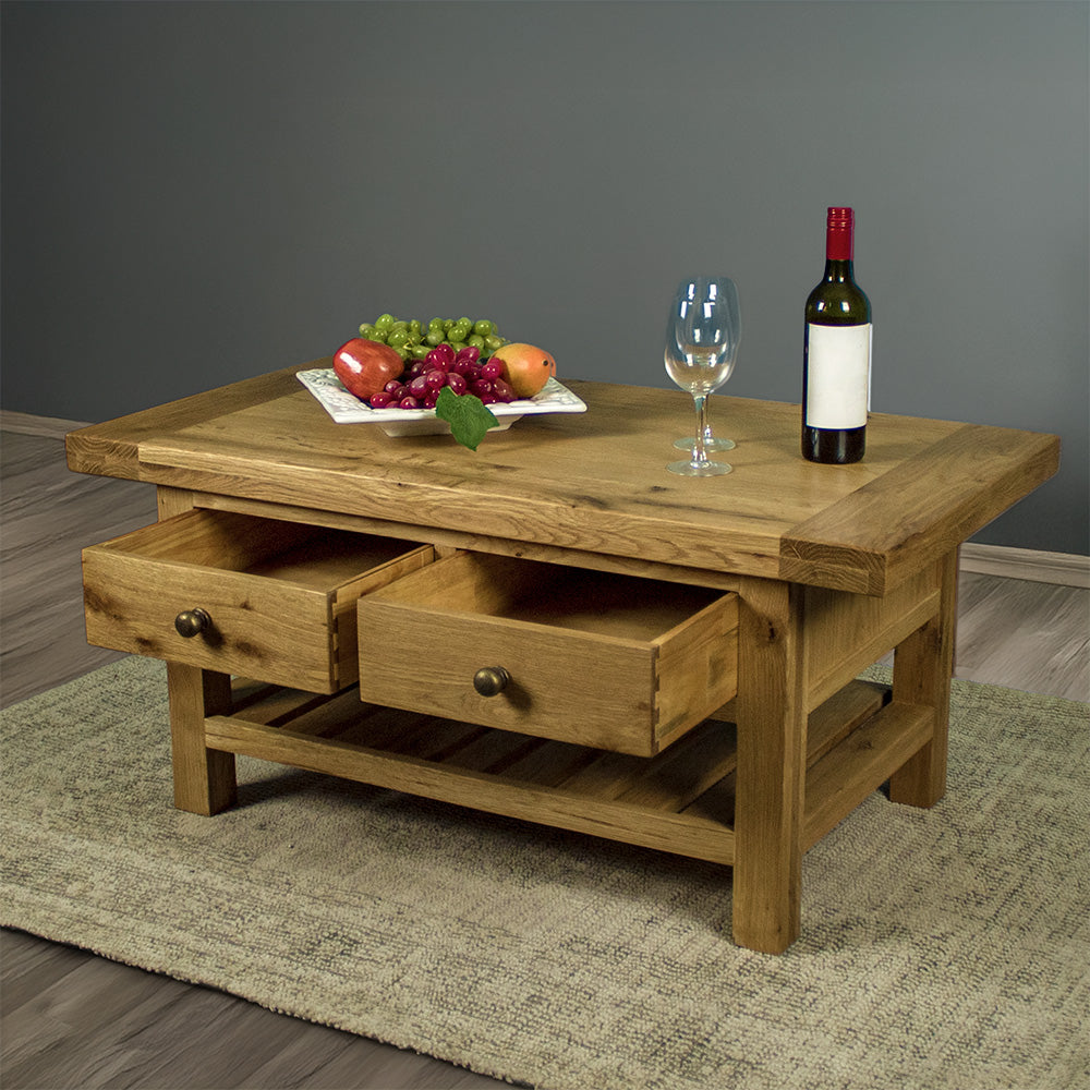 The front of the Farmhouse Coffee Table with its drawers open. There is a fruit platter, two wine glasses and a wine bottle on top.