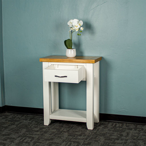 Front of the white Felixstowe Small Pine Hall Table with its drawer open. There is a small pot of white flowers on top.