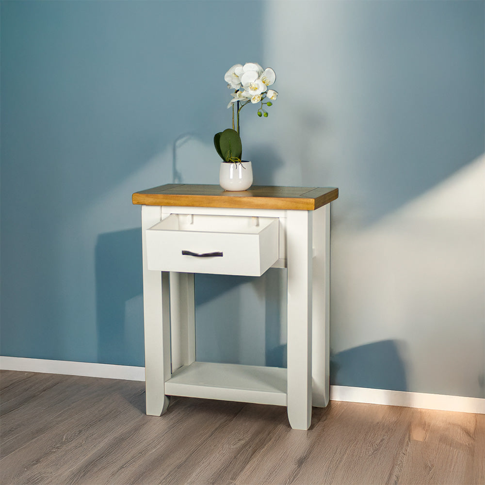 Front of the white Felixstowe Small Pine Hall Table with its drawer open. There is a small pot of white flowers on top.