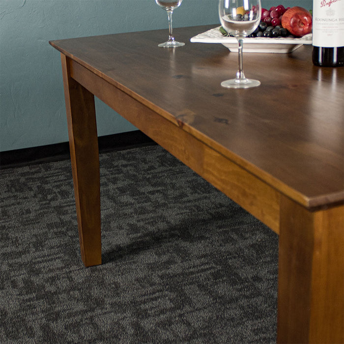 The side of the Hamilton Rimu Stained Dining Table (1500mm). Two wine glasses and a fruit platter can be seen on top of the table.
