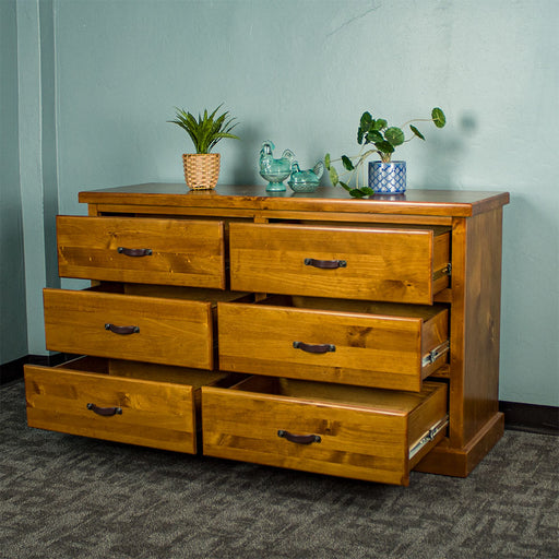 Front view of the Jamaica 6 Drawer Pine Lowboy with its drawers open. There are two potted plants and two blue glass ornaments on top.