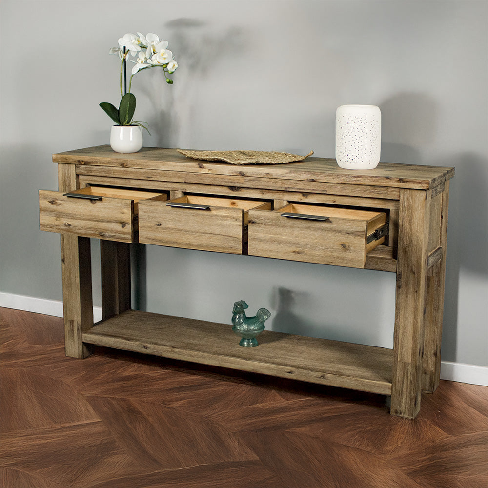The front of the Mars 3 Drawer Console Table with its drawers open. There is a potted plant, a rattan leaf and a white pot on top with a blue glass ornament below.