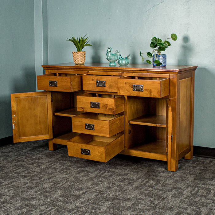 Front view of the Montreal Rimu Stained Buffet/Sideboard with its drawers and doors open. There are two blue glass ornaments and two potted plants on top.