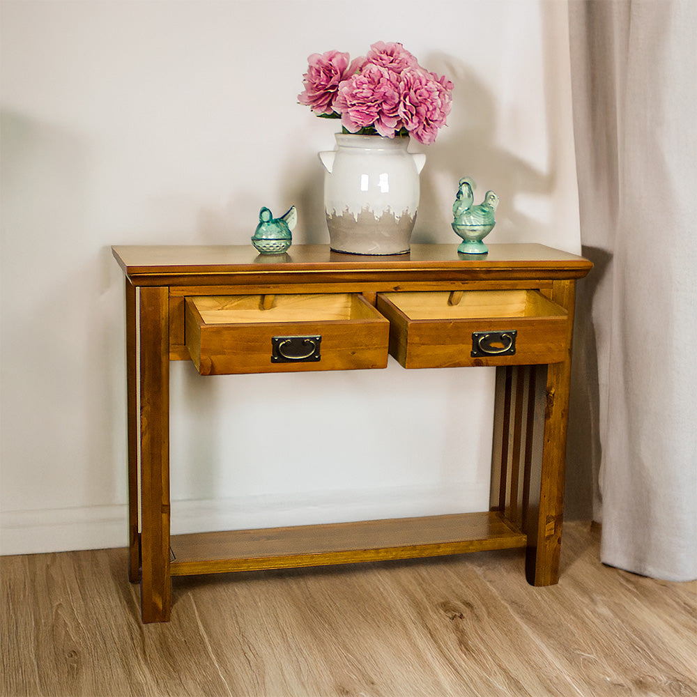 The front of the Montreal Pine Hall Table with its drawers open. There is a large vase on top with two blue glass ornaments on either side.
