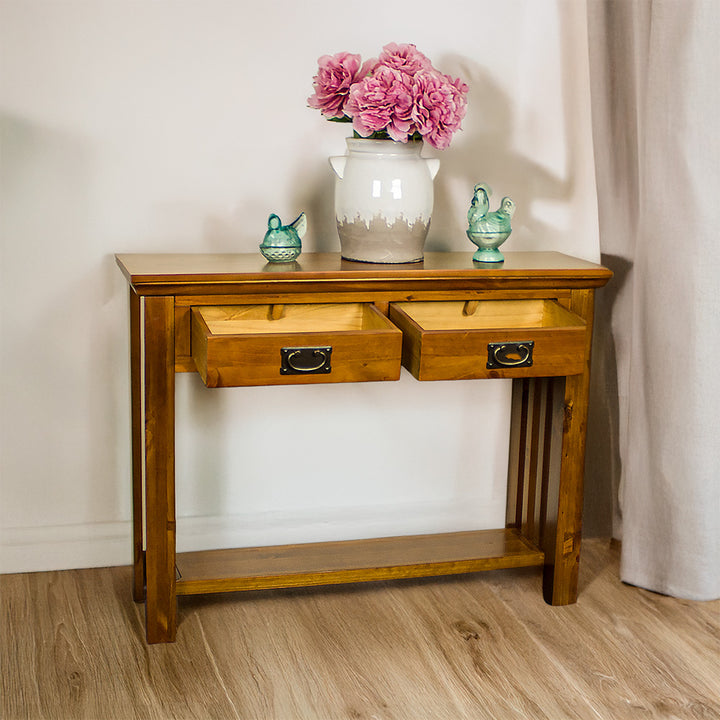 The front of the Montreal Pine Hall Table with its drawers open. There is a large vase on top with two blue glass ornaments on either side.
