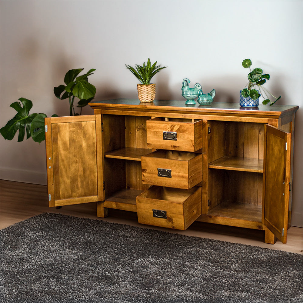 The front of the Montreal Midsize NZ Pine Buffet with its drawers and doors open. There are two potted plants on top with two blue glass ornaments in between.