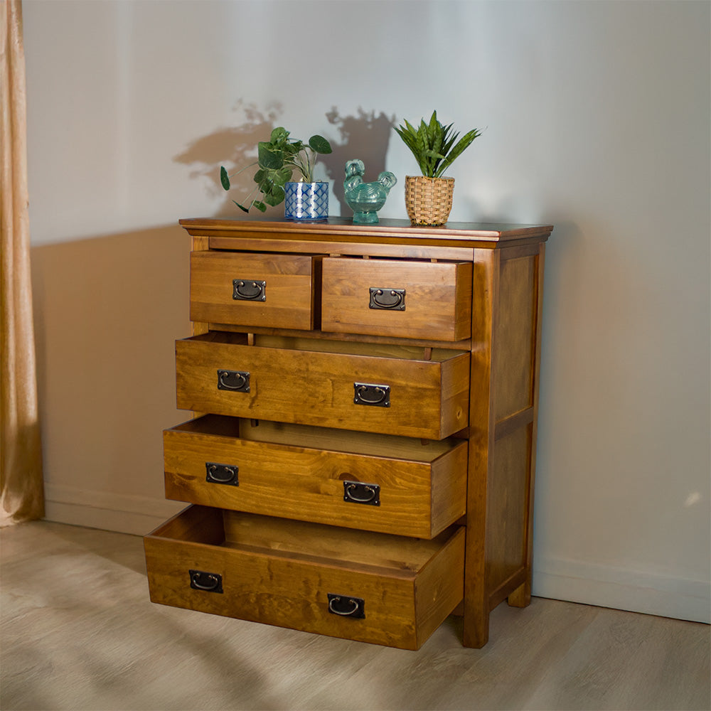 The front of the Montreal Five Drawer Pine Tallboy with its drawers open. There are two potted plants on top and a blue glass ornament in between.