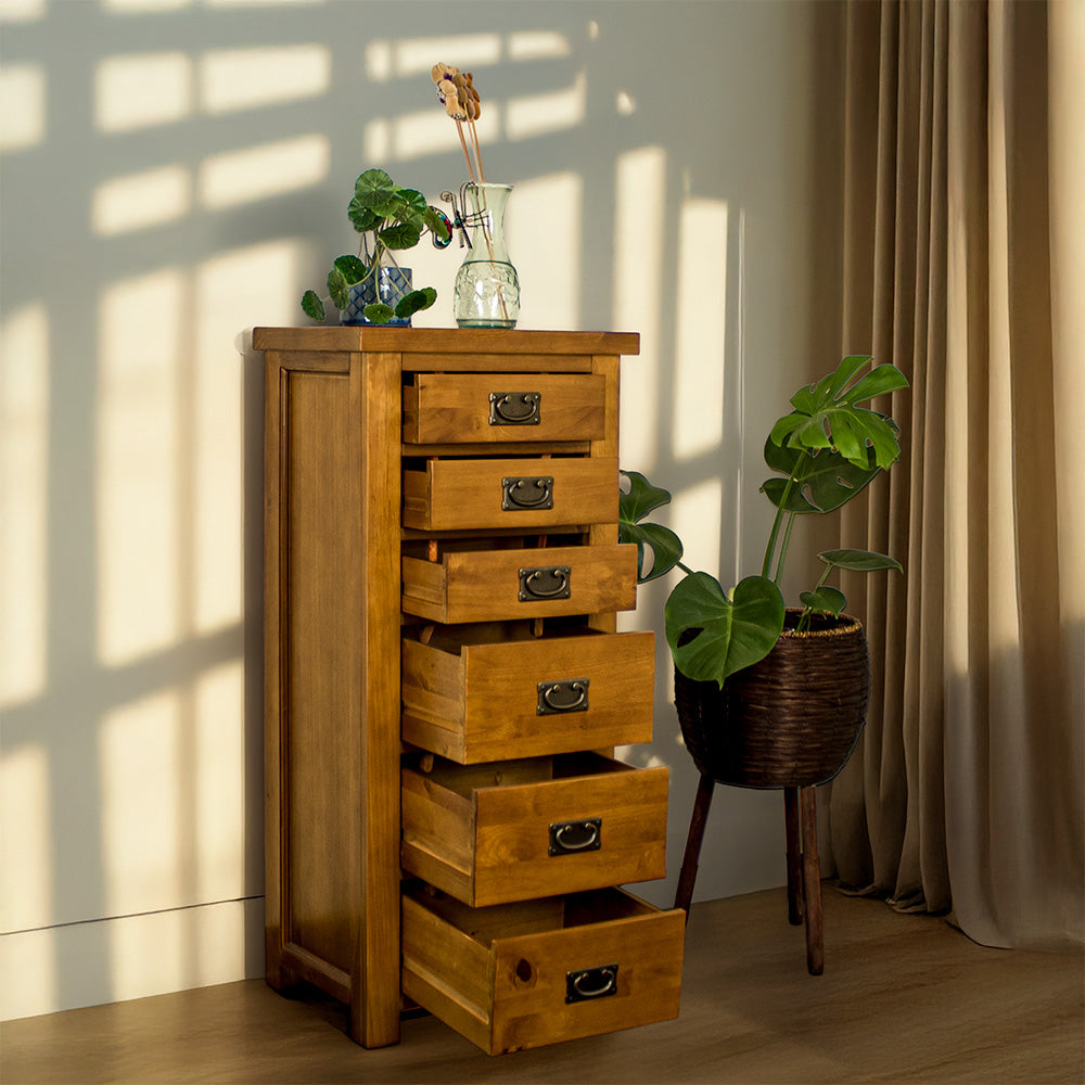The front of the New Quebec 6 Drawer Lingerie Chest with its drawers open. There is a free standing potted plant next to it and a potted plant on top next to a blue glass vase.