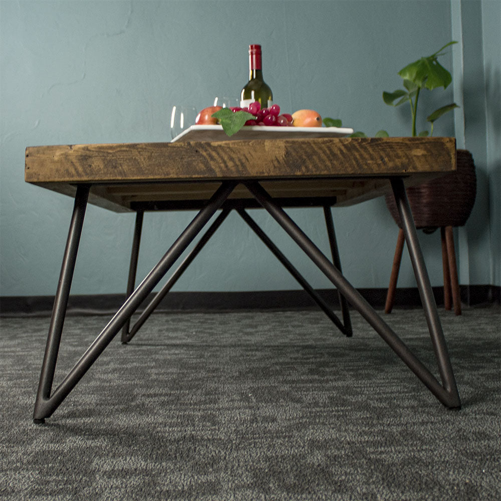 Side of the Paddington Recycled Pine Coffee Table, showing the black metal cross legs. There is a fruit platter on top.