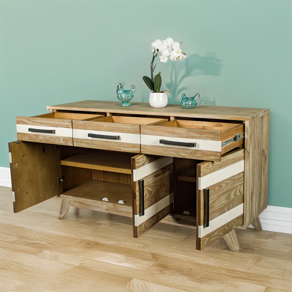 The front of the Soho 3 Drawer NZ Pine Large Buffet with its doors and drawers open. There are two blue glass ornaments on top with a pot of white flowers in between.