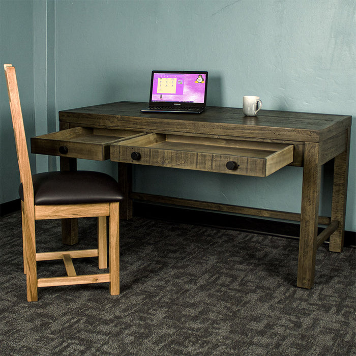 Front of the Stonemill Recycled Pine Desk with its two drawers open. There is an oak leather chair in front and a laptop and coffee mug on top.