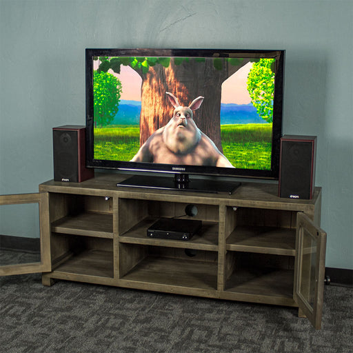 The front of the Stonemill Recycled Pine TV Unit with its doors open and a TV and two speakers on top. There is a DVD player in the top shelf in the middle.