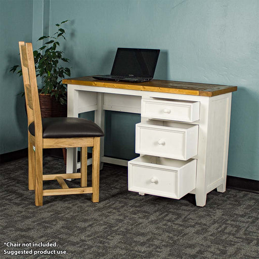 The front of the Tuscan Recycled Pine Small Desk with its drawers open. There is a laptop on top and an oak upholstered dining chair in front. There is a free standing potted plant next to it.