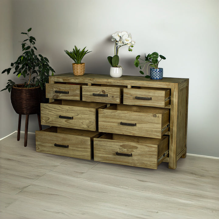 The front of the Vancouver 7 Drawer NZ Pine Lowboy with its drawers open.  There are three potted plants on top and a free standing potted plant next to the lowboy.