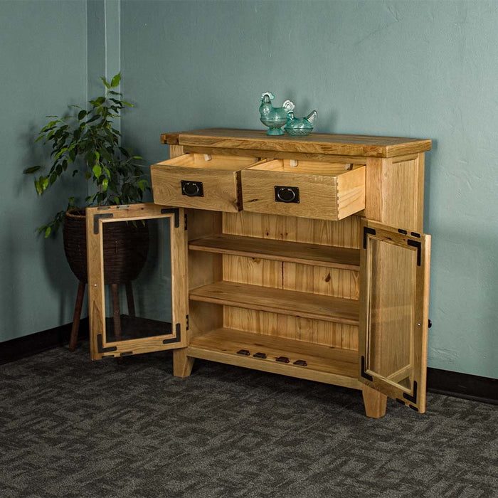 The front of the Vancouver Value 2 Drawer 2 Door Oak Sideboard, with its drawers and doors open. There are two blue glass ornaments on top and a free standing potted plant next to the buffet.