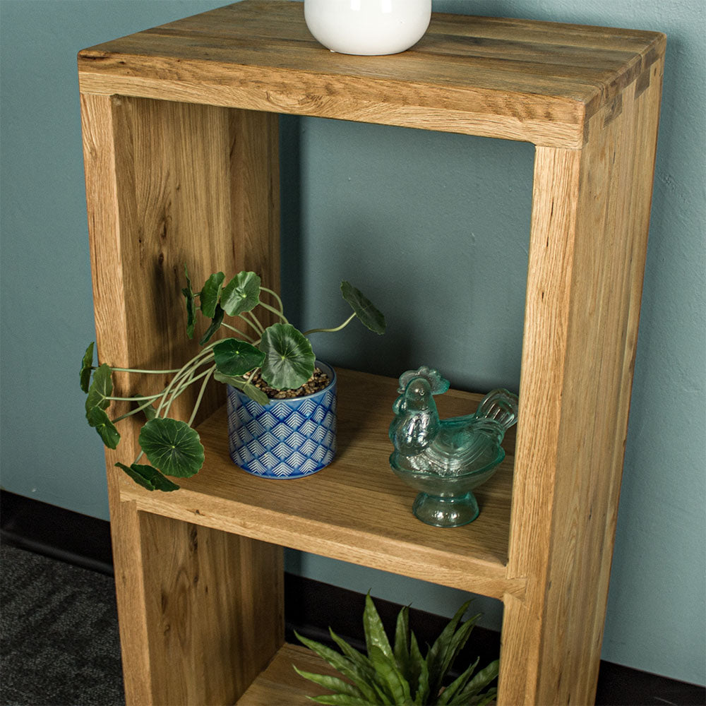 The top shelf of the Vancouver Value Double Cube Oak Shelf with a potted plant and a blue glass ornament sitting on it.