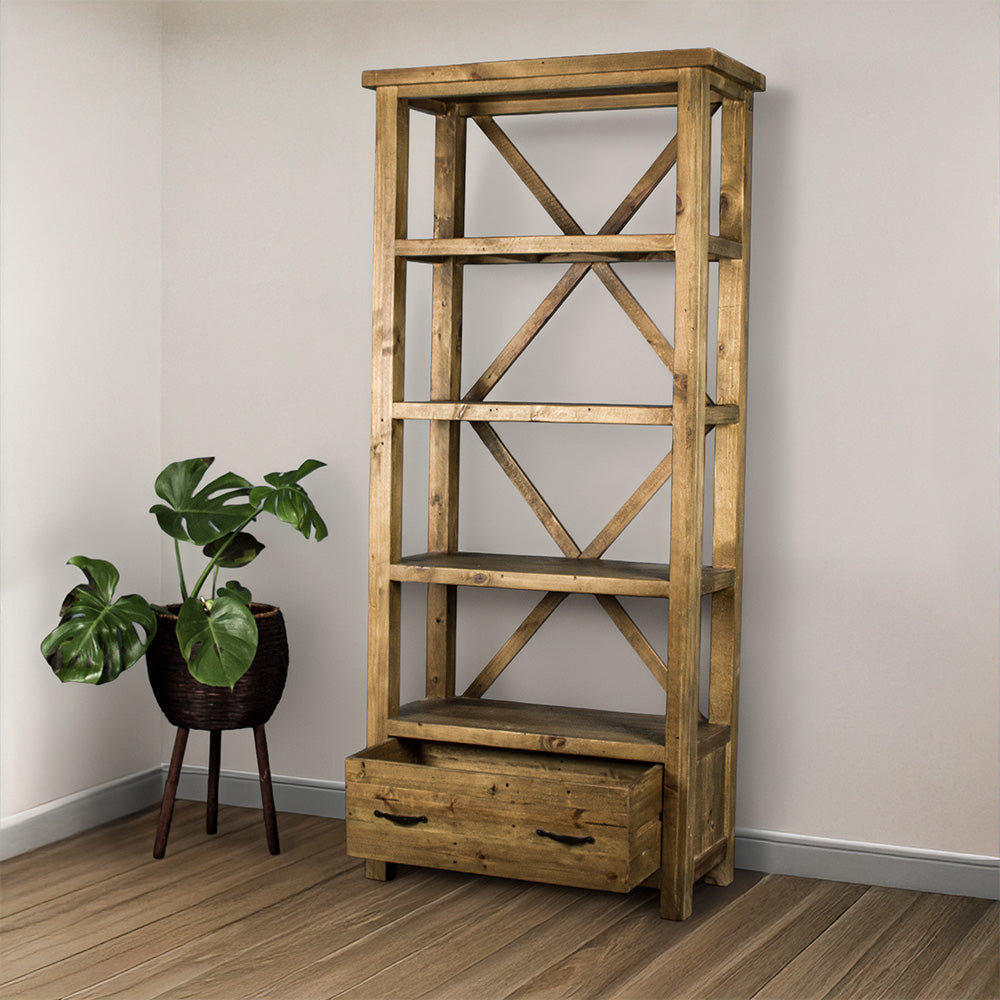 The light brown Ventura Recycled Pine Bookcase with its drawer open, and a standing potted plant next to it. 